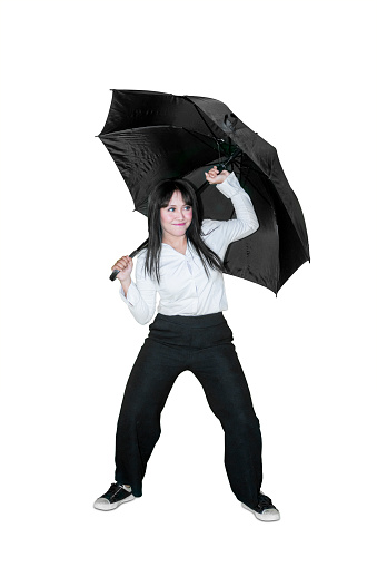 Happy businesswoman holding an umbrella while dancing in the studio. Isolated on white background
