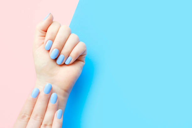 istock Female hands with light blue manicure on blue and pink background with copy space. 1481565432