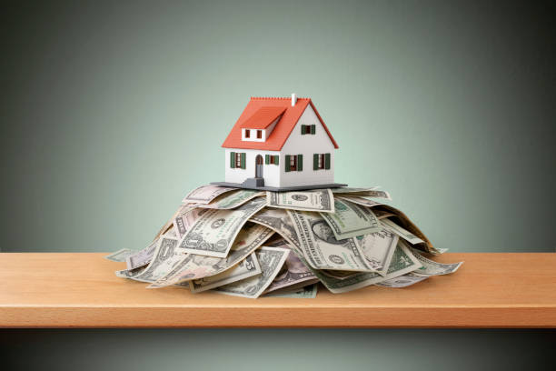 istock Miniature model house standing on a heap of dollar bills 1481568583