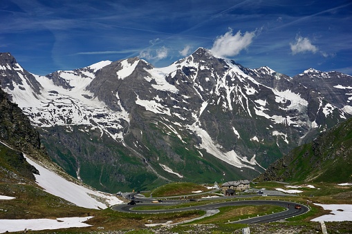 The Grossglockner High Alpine Road in late spring. The Alps in sunny weather. The Austrian Alps under a blue sky. Snow-capped peaks of mountains, and green grass below. Spring in the Alps. The peaks of the Alps under a blue sky.