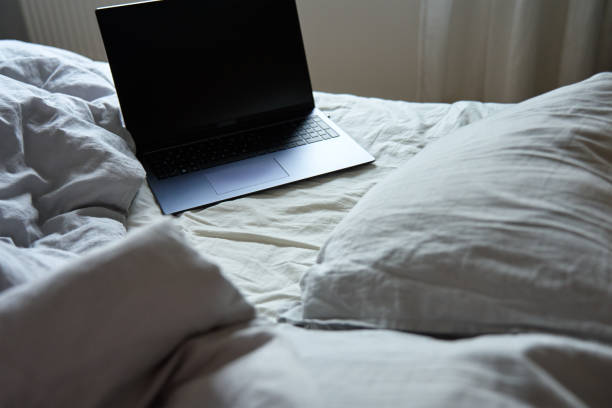 istock Unmade bed with pillows and crumpled bedsheets and open laptop 1481570056