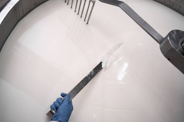 Cheese maker making traditional cheese at a creamery, cutting the curds and whey. Close-up Cheese maker making traditional cheese at a creamery, cutting the curds and whey. Close-up. Top view dairy producer stock pictures, royalty-free photos & images