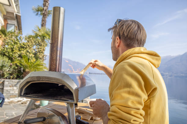 istock Man adding wood to wood fire pizza oven 1481577953
