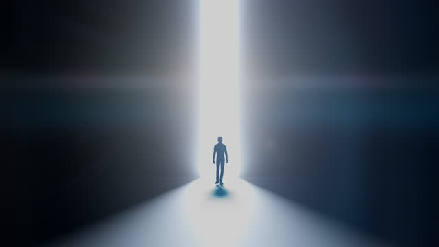 A man walking into the darkness from a beam of light