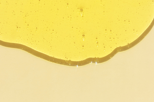 The texture of an antibacterial yellow gel or shampoo on a beige background. Serum or hyaluronic acid with bubbles. The concept of protection against viruses or cosmetics.
