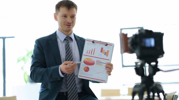 istock Business coach blogger showing graphs on documents in front of camera in office 1481582683
