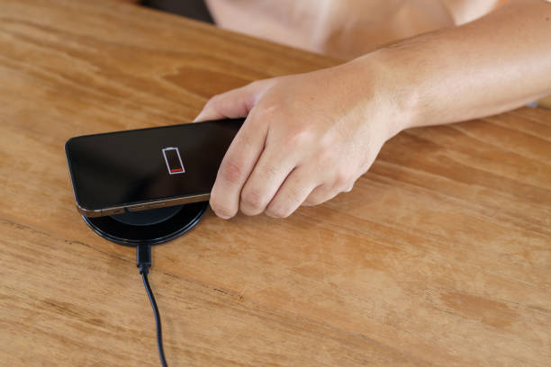 istock Charging mobile phone battery with wireless charging device in the table. Smartphone charging on a charging pad. Mobile phone near wireless charger Modern lifestyle technology concept. 1481586379