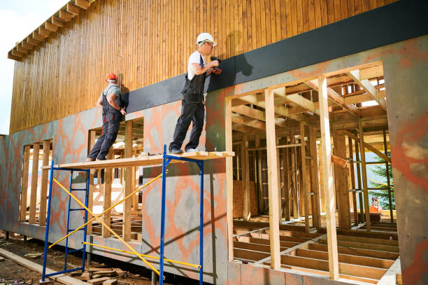 istock Workers cladding facade of house with cement particle boards while constructing wooden frame house. 1481587071