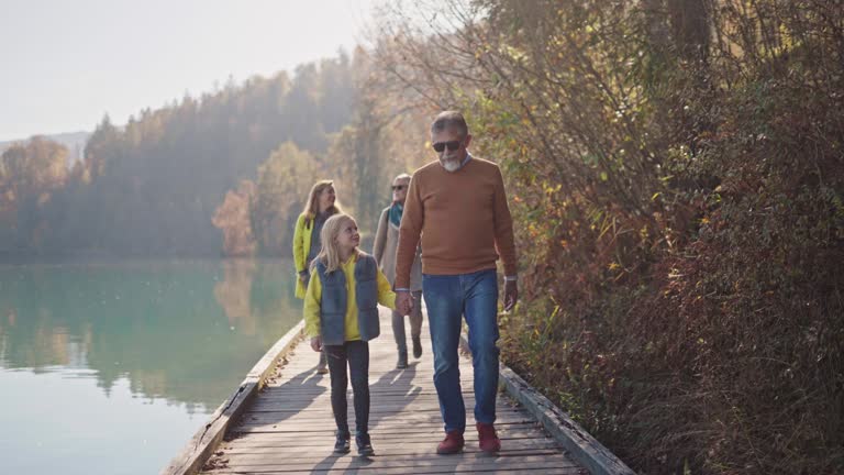 Good Looking Caucasian Family Walking Around A Lake While Enjoying A Sunny Autumn Day