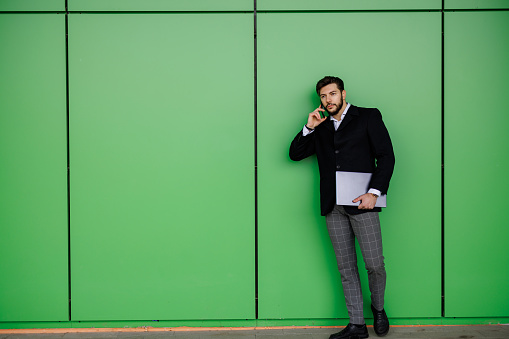 Full length shot of young businessman talking on smart phone on green background