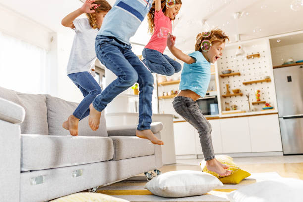 istock Playful kids having fun while jumping from sofa at home. 1481600194