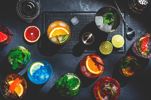 cocktail impostati sul bancone del bar nero, vista dall'alto. concetto di mixology. assortimento di bevande colorate forti e a bassa gradazione alcolica per cocktail party. sfondo scuro, strumenti da barra, luce dura - fruit liqueur foto e immagini stock