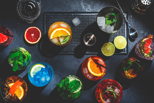 Cocktails set on black bar counter, top view. Mixology concept. Assortment of colorful strong and low alcohol drinks for cocktail party. Dark background, bar tools, hard light stock photo