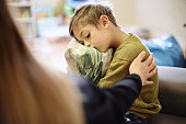 Anxiety, bullying and hand of mother with boy hugging pillow for comfort, compassion and empathy at home. Disability, abuse and mom with sad child suffering depression or mental health problem