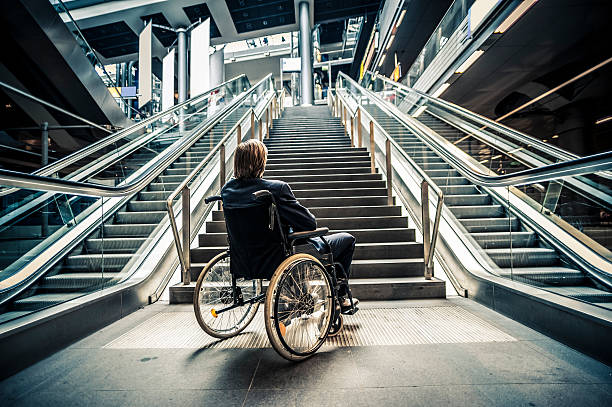 Businessman on a wheelchair against modern stairs stock photo