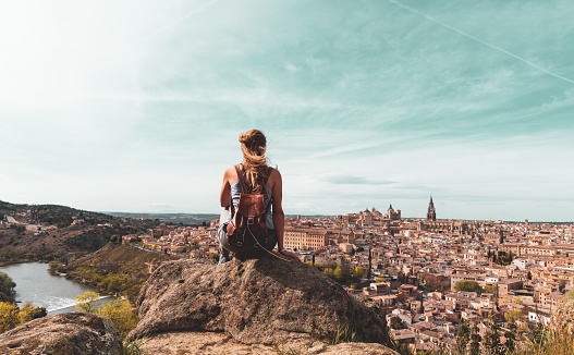 Woman tourist sitting on peak and looking at panoramic view of Toledo- Famous city in Spain