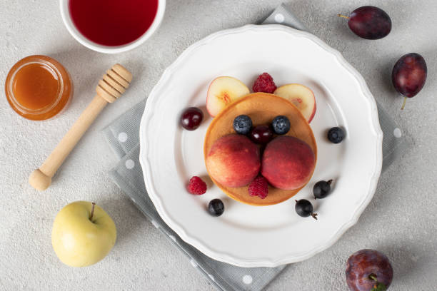 Pancakes with fruits and berries in the shape of cat - funny idea for children's breakfast stock photo