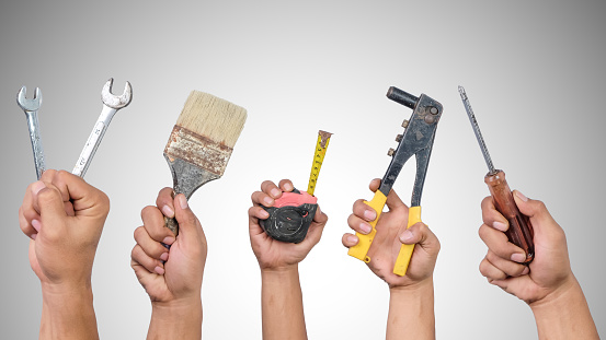 Hands holding different carpentry tools isolated on white background.