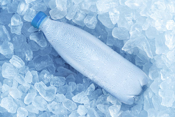 garrafa fria de água sobre cubos de gelo. fundo de comida e bebida. - água congelada - fotografias e filmes do acervo