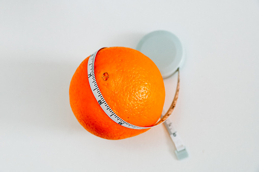 An orange and a sewing ribbon around it