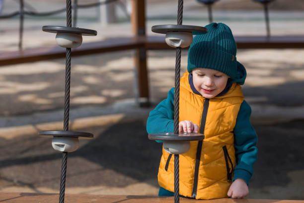 un niño pequeño camina en la primavera en el patio de recreo. el niño se está divirtiendo jugando al aire libre en un soleado día de primavera. infancia y desarrollo infantil. - 2 3 months beginnings new life caucasian fotografías e imágenes de stock