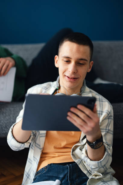 istock Happy Teenager Using A Digital Tablet With His Unrecognizable Brother At Home 1481612851