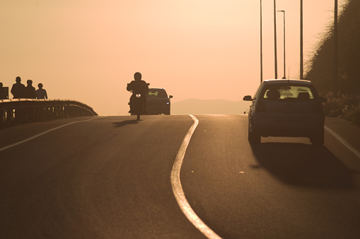 Motorcycle and cars circulating on the road at sunset