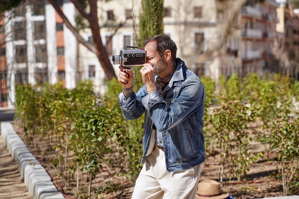 Old school filmmaker shooting with vintage camera A man with a passion for film captures images with an old school camera vintage amateur movie camera stock pictures, royalty-free photos & images