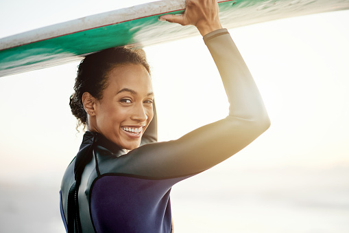 Smile, surfer or portrait of woman at sea for fitness training, workout or sports exercise at sunset. Surfing, surfboard or happy mixed race athlete smiling on fun summer holiday vacation on beach