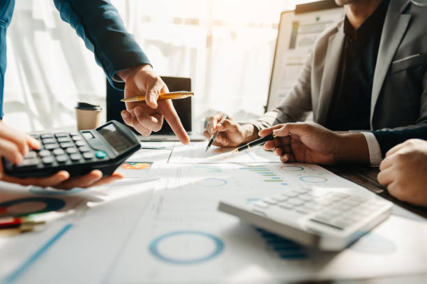 istock Business documents on office table with smart phone and calculator digital tablet and graph business with social network diagram and two colleagues discussing data working in the office 1481624108