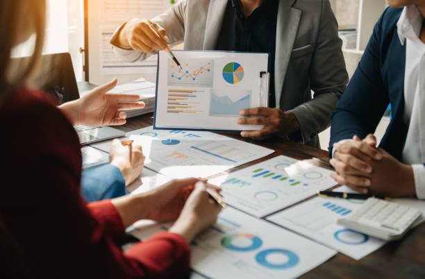 istock Business documents on office table with smart phone and calculator digital tablet and graph business with social network diagram and two colleagues discussing data working in the office 1481624114