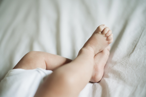 Baby feet, closeup and infant foot on a nursery bed ready for sleeping, morning rest and nap. Children room, young kid and bedroom blanket of a child in a family home with newborn legs in a house
