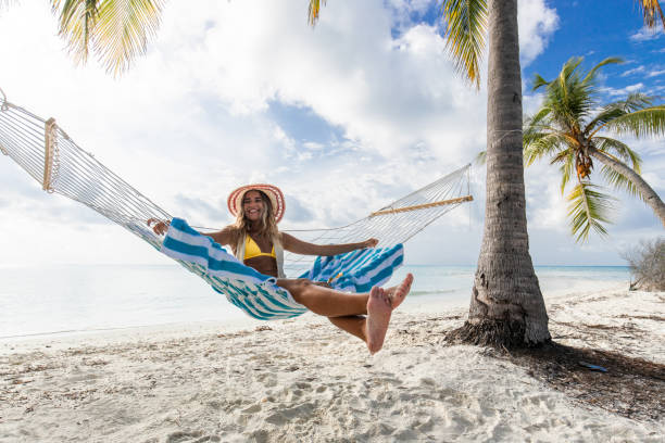 해변에서 해먹에서 즐기는 젊은 행복한 여성. - hammock beach vacations tropical climate 뉴스 사진 이미지