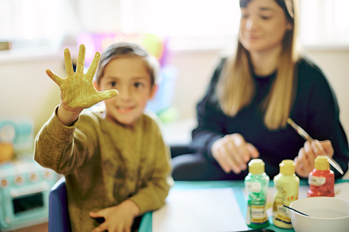 Painting, hand and art with child and teacher in classroom for learning, education and creative. Inspiration, lesson and color with young boy and woman at school for teaching, drawing and hobby