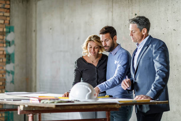istock Young couple and their agent examining blueprints at construction site. 1481626864
