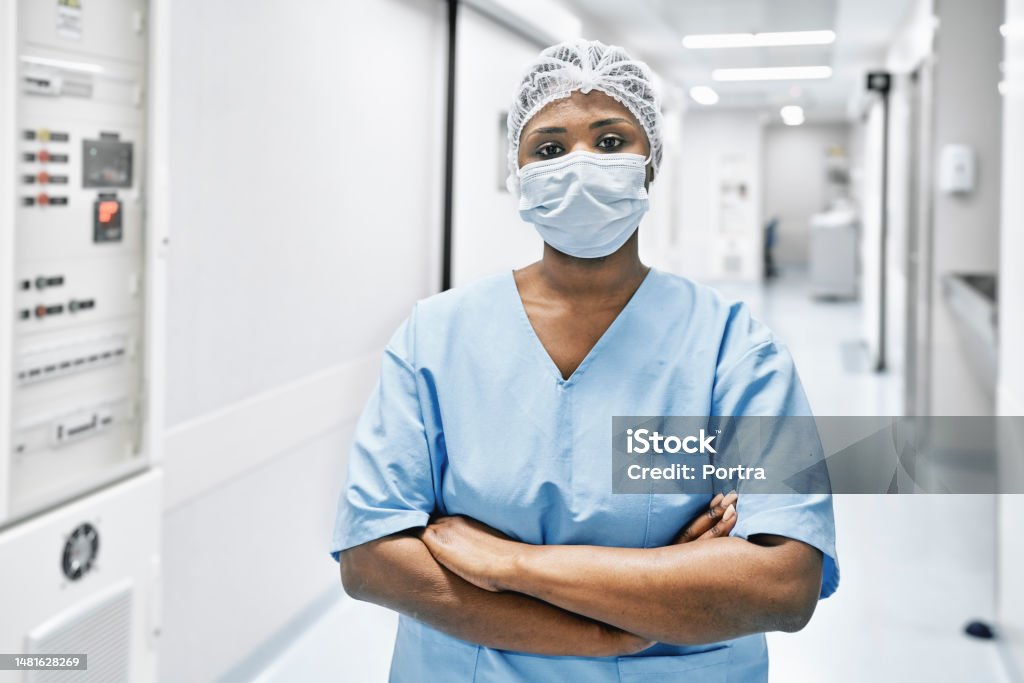 African woman doctor in uniform standing at hospital corridor Portrait of a female nurse wearing surgical mask and cap. African woman doctor in uniform standing at hospital corridor. Female Doctor Stock Photo