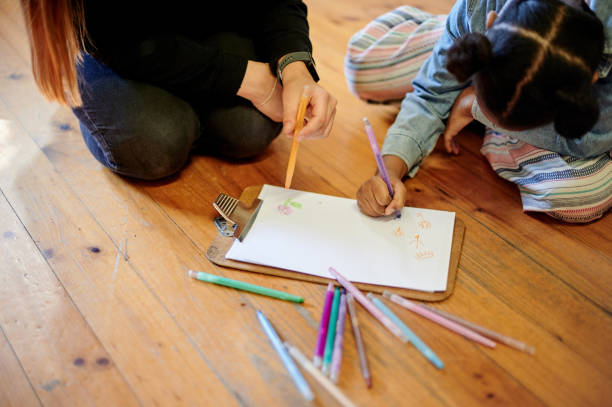 istock Creative, drawing and art with kid and teacher on floor of classroom for learning, education and teaching. Color, sketching and child development with young girl and woman at school for picture 1481630385