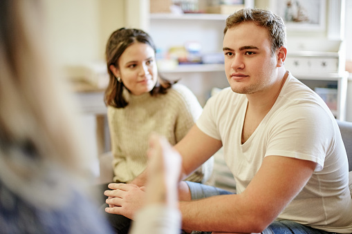 Mental health, support and talking, couple in therapy with understanding in marriage counselling and sharing feelings. Psychology, man and woman sitting on couch together with therapist for advice.