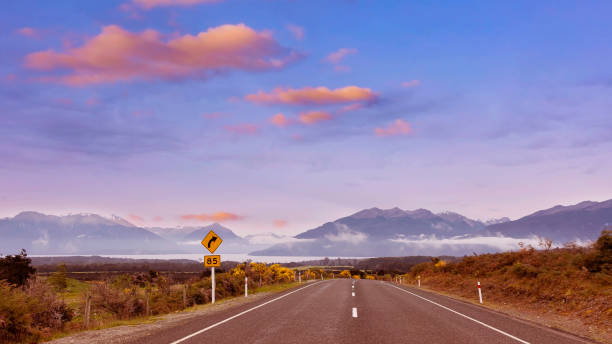 a vista da viagem rodoviária da viagem com vista para a montanha da cena do outono e nebulosa pela manhã com a cena do céu do nascer do sol no parque nacional fiordland - sunrise new zealand mountain range mountain - fotografias e filmes do acervo