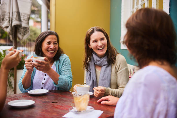 istock Mature women talking and laughing over coffee at a sidewalk cafe 1481634841
