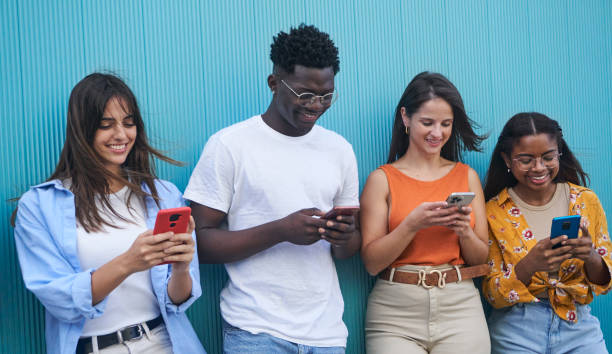 istock Group of multiethnic young people using mobile phone standing outdoor against blue wall. 1481640688