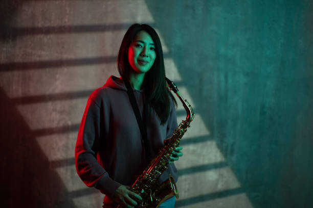 Portrait of a beautiful Japanese female saxophonist in studio.