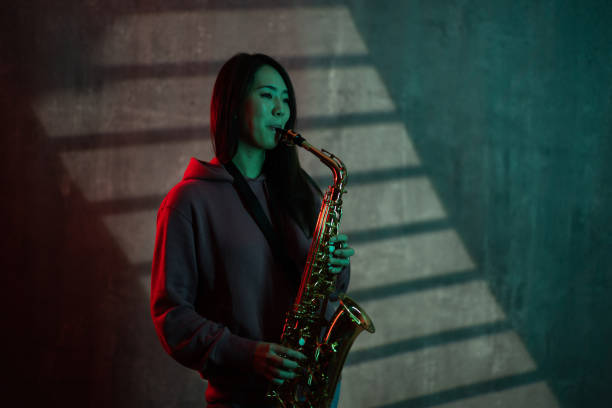 Portrait of a beautiful Japanese female playing saxophone in studio.