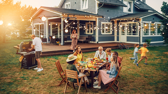 Gran familia y amigos celebrando afuera en casa. Un grupo diverso de niños, adultos y ancianos se reunieron en una mesa, teniendo conversaciones divertidas. Preparar barbacoa y comer verduras. photo