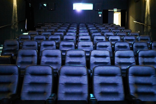 Interior of movie theater with empty leather seats and projector