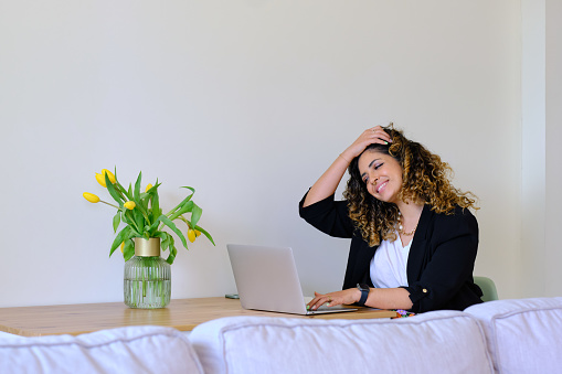 lateral view portrait of a well dressed and carefree young woman using a laptop for learn at home
