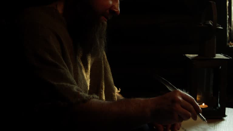 A man writes with an ink pen with a feather