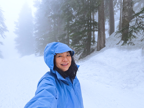 Selfie of solo Chinese woman in 60s snowshoeing at Mt. Seymour, North Vancouver, British Columbia, Canada.