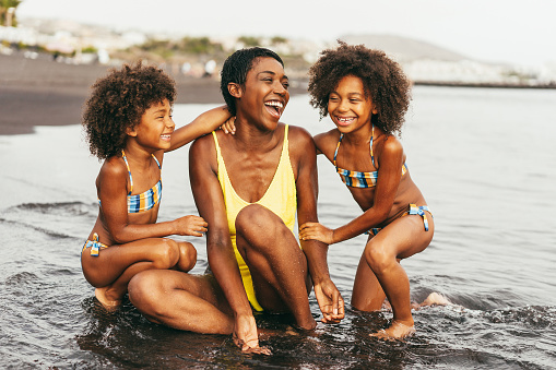 African sister twins having fun with mother on the beach - Soft focus on right girl face