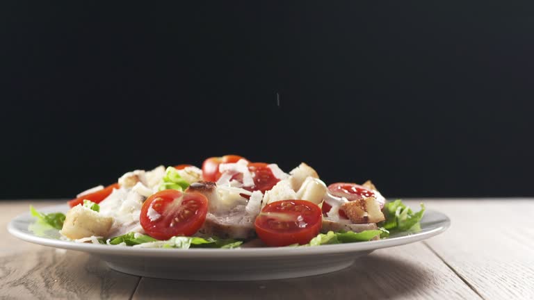 grated parmesan falling onto caesar salad in slow motion